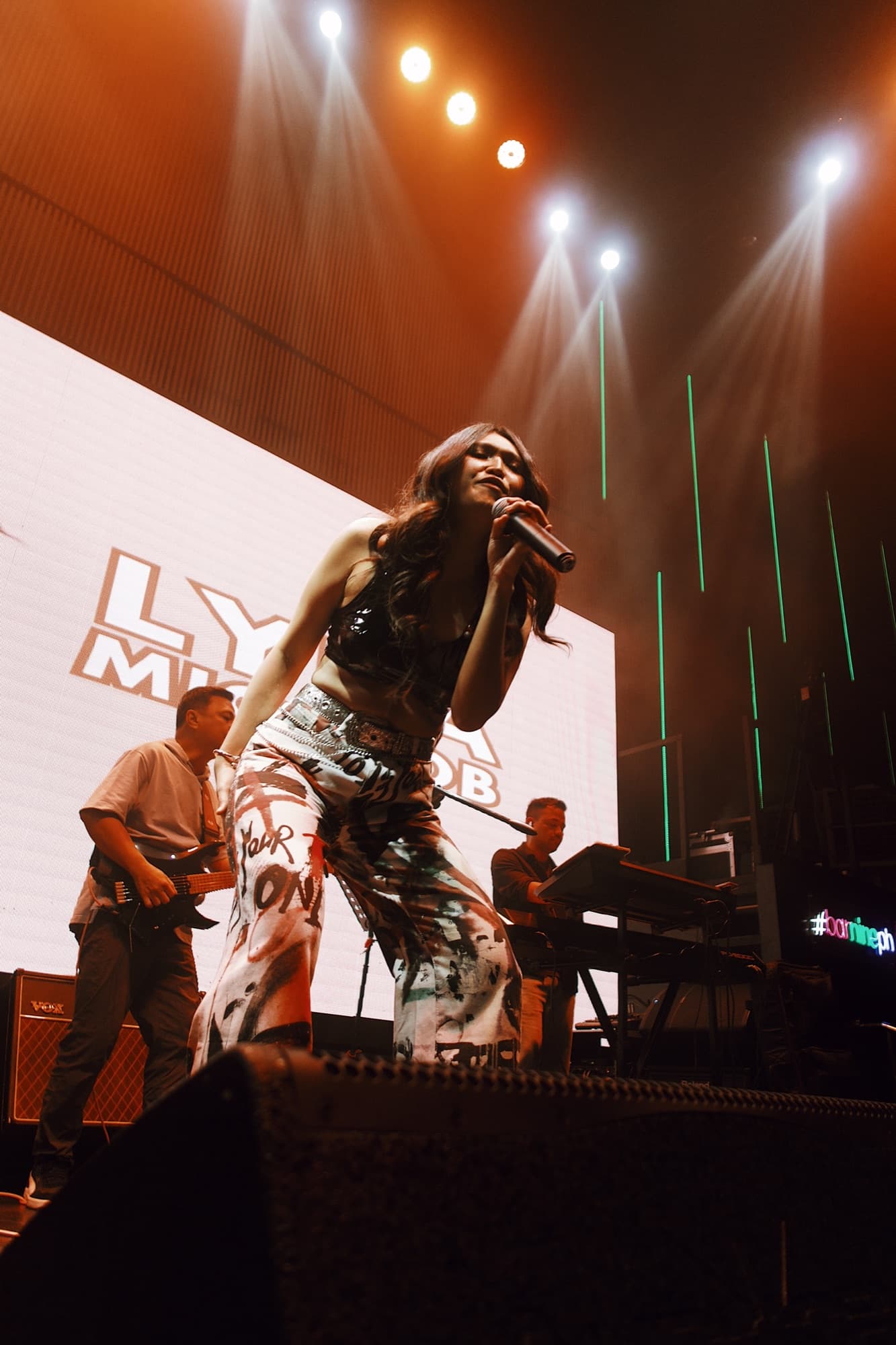 Lyra performing with her band under stage lights