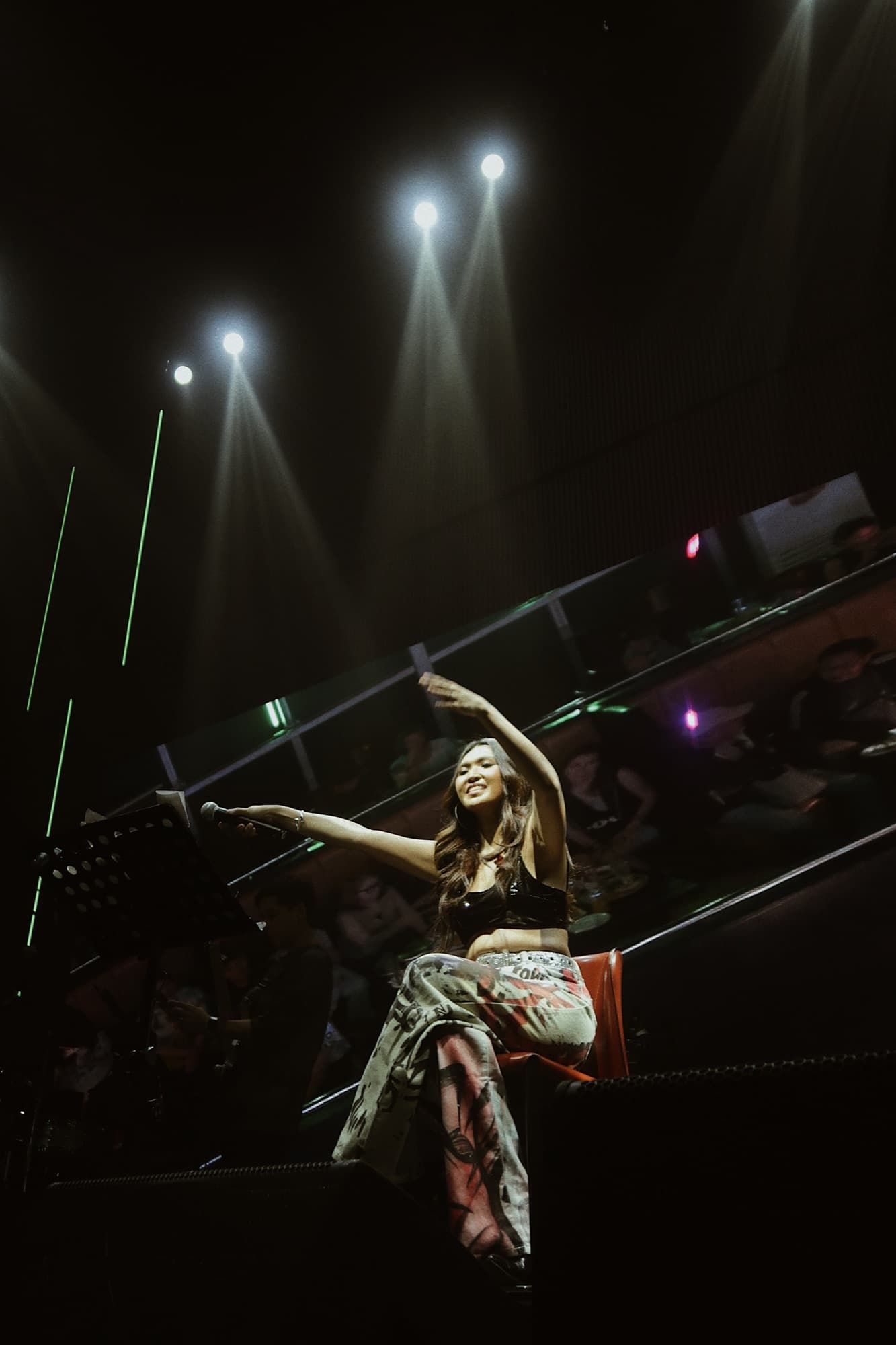 Lyra reaching out to the crowd under spotlights