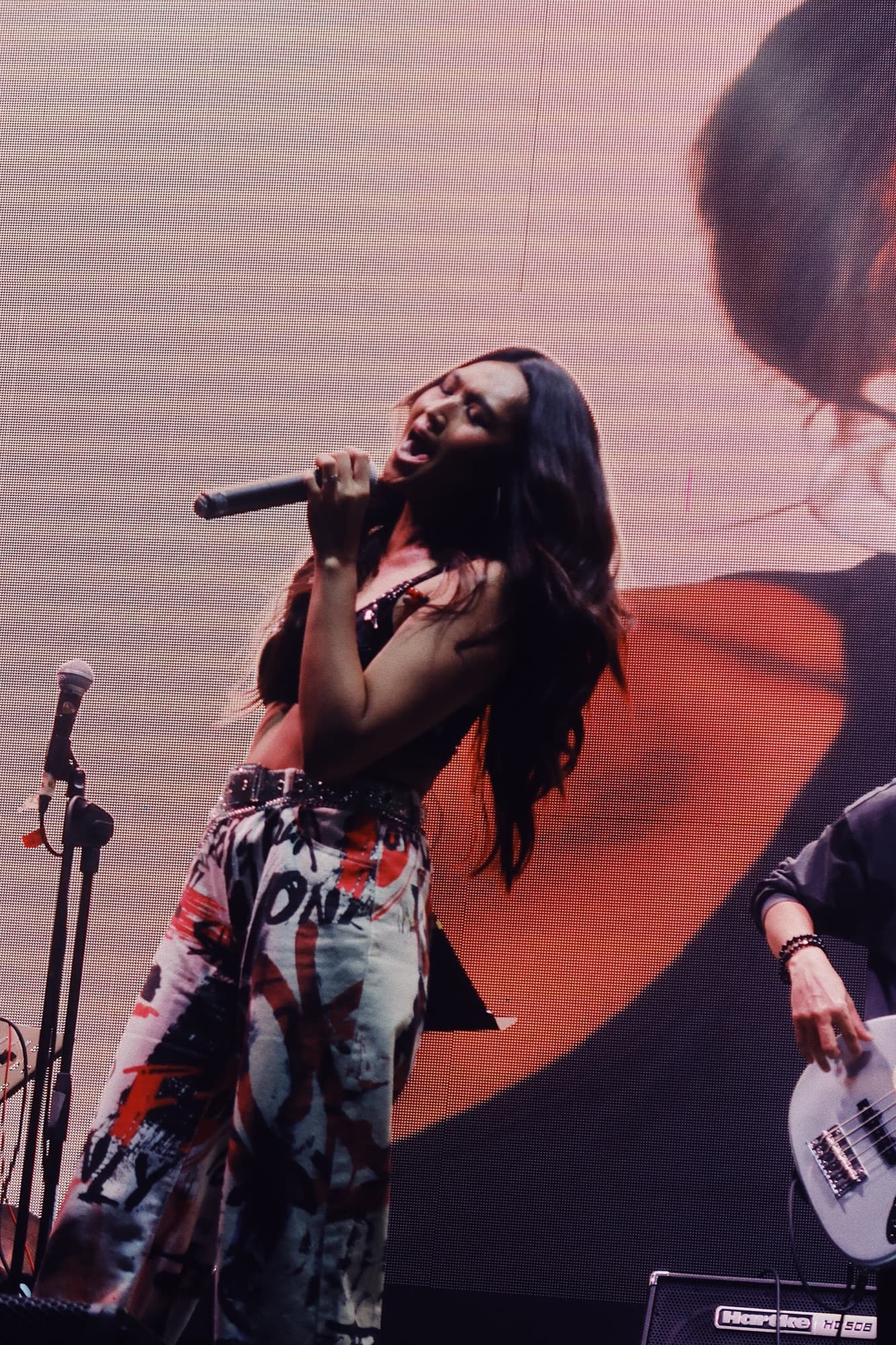 Lyra singing on stage in front of a giant screen
