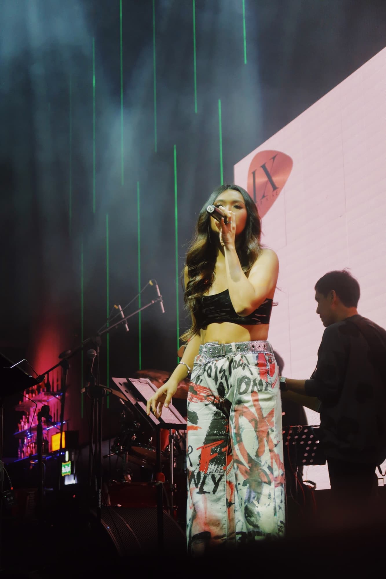 Lyra singing on stage with green stage lights